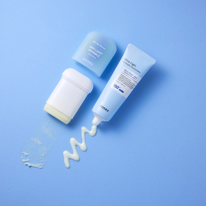 COSRX Airy-Light Invisible Sun Stick 19 g solkrem SPF 50 i stift og tube med hvit kremtekstur på blå bakgrunn