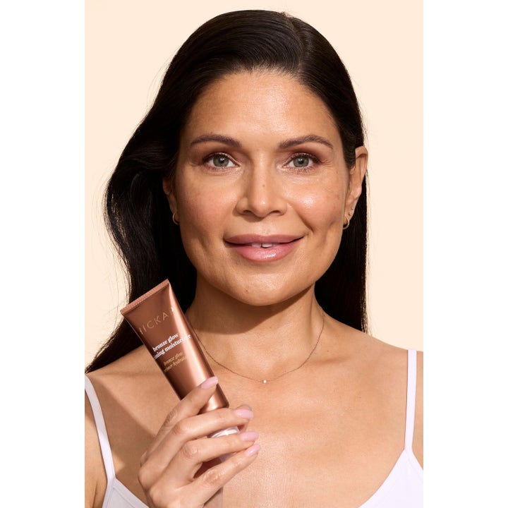 Hickap Bronze Glow Priming Moisturizer 50 ml fuktighetskrem gir glød vist av kvinne med bronsefarget tube.