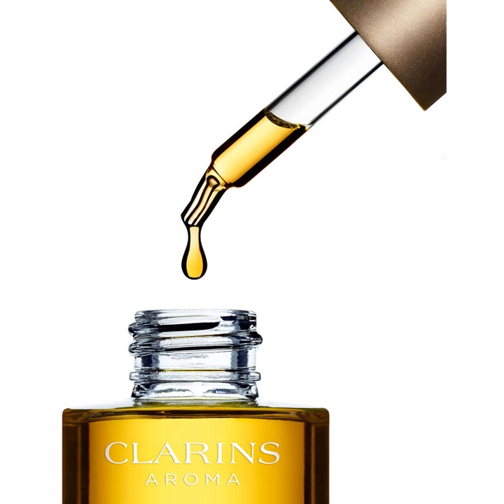 Clarins Santal Face Treatment Oil 30 ml beroligende ansiktsolje i glassflaske med en gyllen dråpe fra pipetten