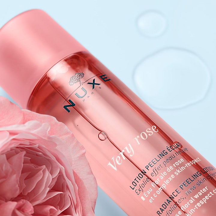 Nuxe Very Rose Peeling Lotion 150 ml eksfolierende ansiktsvann ved siden av en rosa rose og vanndråper