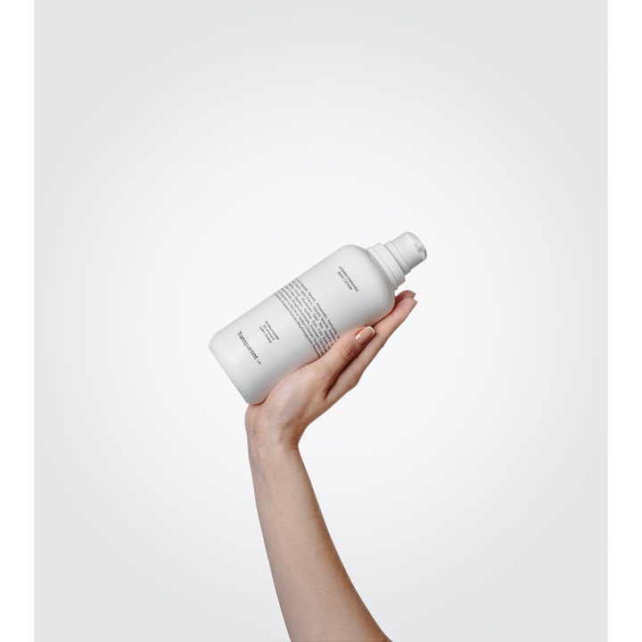 Niche Beauty Lab Transparent Lab Vitamin Enriched Body Lotion 400 ml fuktighetskrem i hvit flaske holdt av en hånd