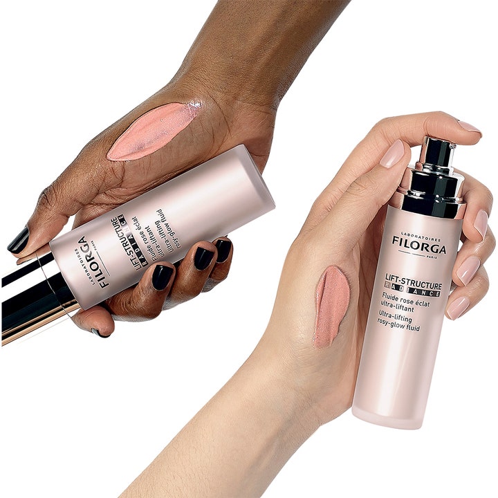 Filorga Lift-Structure Radiance 50 ml løftende flytende dagkrem med rosa tekstur på to hender