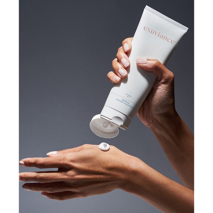 Exuviance Gentle Cream Cleanser 212 ml ansiktsrens for tørr hud som klemmer ut hvit kremet tekstur på en hånd.