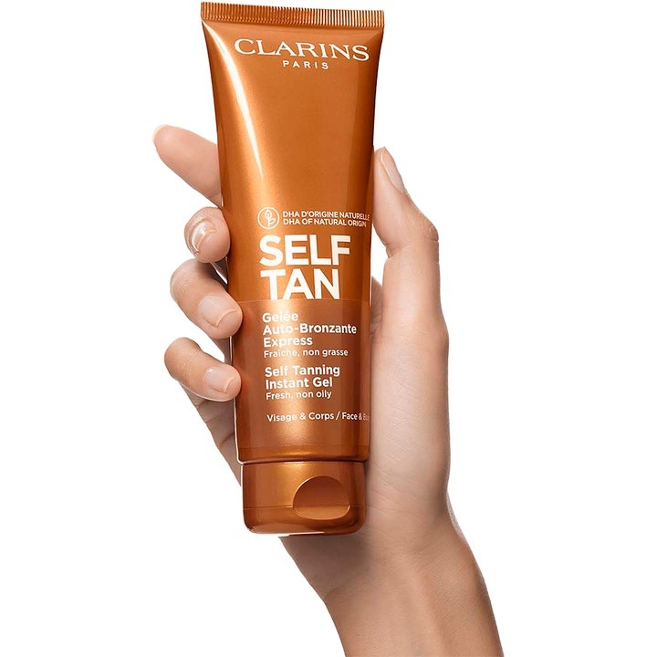 Clarins Self Tanning Instant Gel 125 ml gir naturlig glød i en bronsefarget tube holdt av en hånd