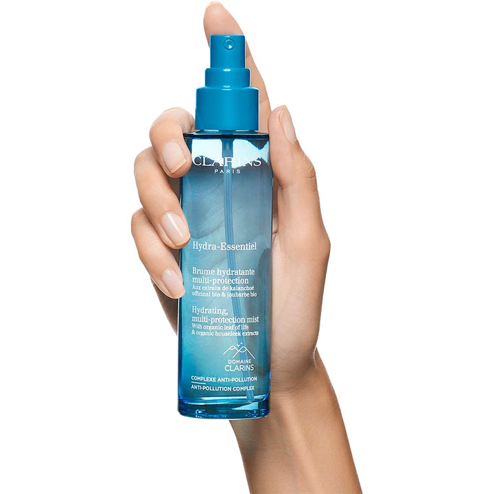 Clarins Hydra-Essentiel 75 ml fuktighetsgivende face mist med anti-pollution i blå flaske holdt av en hånd