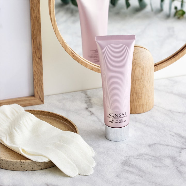 Sensai Cellular Performance Intensive Hand Treatment 100 ml pleiende håndkrem i rosa tube ved en hvit bomullshanske.
