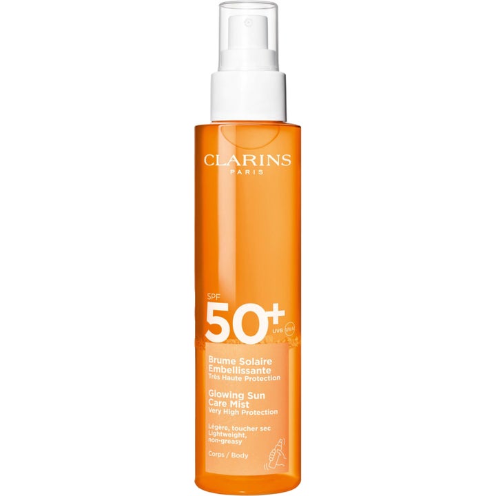 Clarins Glowing Sun Care Mist SPF 50+ 150 ml solspray som gir glød i en slank oransje flaske med hvit pumpe.