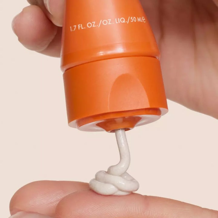 Origins GinZing SPF40 50 ml farget dagkrem på oransje tube med hvit bølge av kremet tekstur.