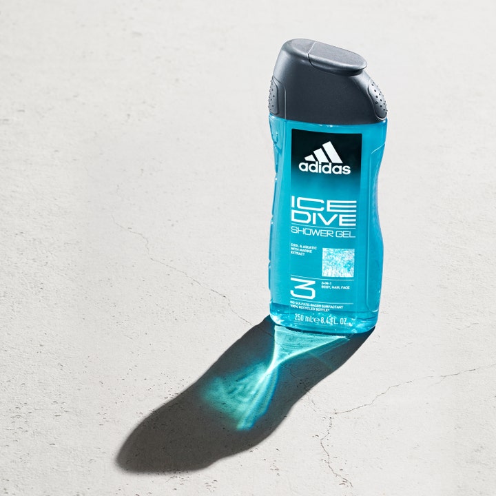 Adidas Ice Dive 250 ml dusjsåpe for ansikt og kropp i blå flaske som kaster lyseblå skygge på grått gulv