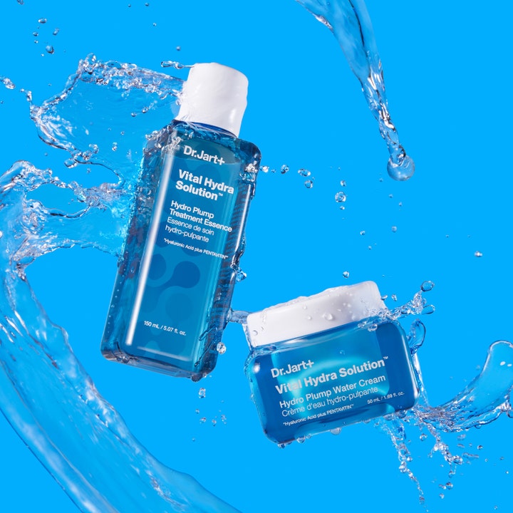 Dr.Jart+ Vital Hydra Solution Essence 150 ml og ansiktskrem omgitt av sprutende vann på blå bakgrunn