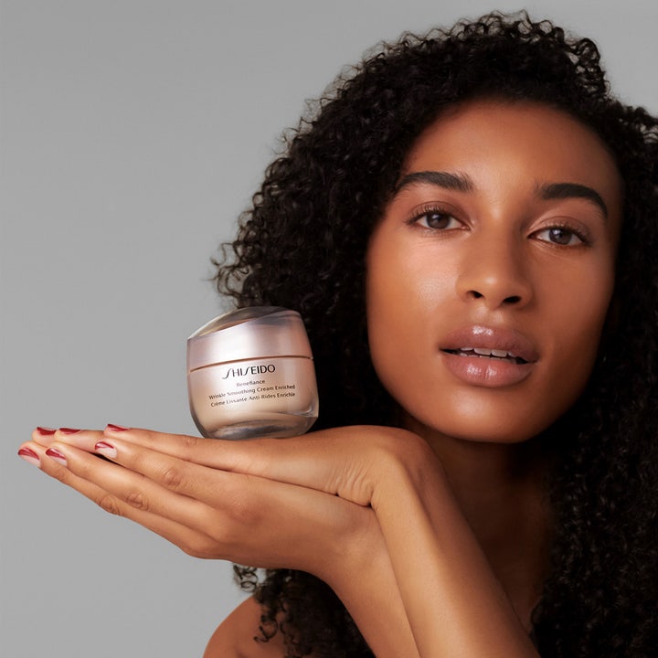 Shiseido Benefiance Wrinkle Smoothing Enriched Cream 50 ml rynkereduserende dagkrem i beige krukke holdt av modell.