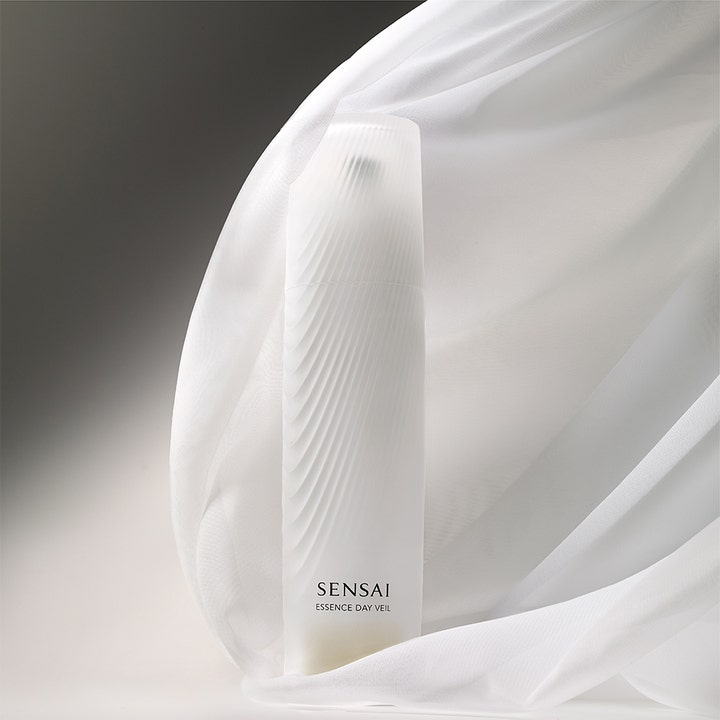 Sensai Essence Day Veil 40 ml fuktighetsgivende dagkrem i hvit riflet flaske drapert i florlett hvitt stoff.