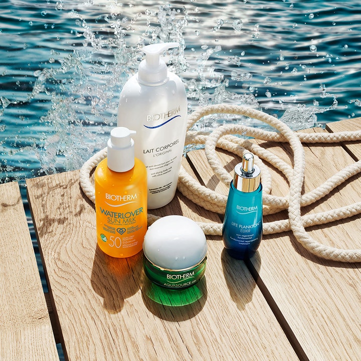 Biotherm Waterlover Sun Milk 200 ml solkrem i oransje pumpeflaske på en solfylt trebrygge ved vannet.