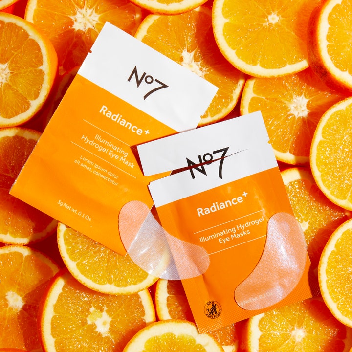 No7 Radiance+ Illuminating Hydrogel Eye Masks 5 stk glødgivende øyemasker på en bakgrunn av friske appelsinskiver.