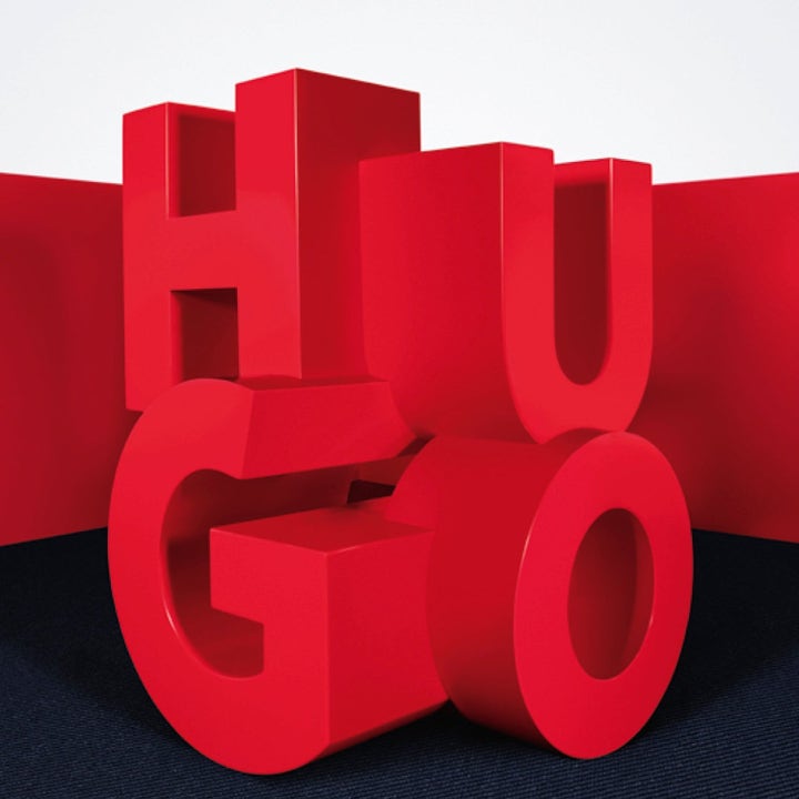 Hugo Boss Hugo Duo 2 x 75ml deodorantstick med store røde 3D-bokstaver som staver HUGO mot mørkt gulv.