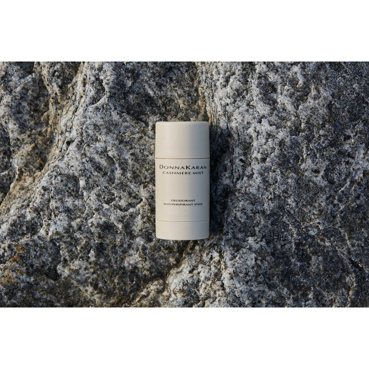 Donna Karan Cashmere Mist Deodorant Anti-Perspirant Stick beige hylse plassert på en naturlig grå stein