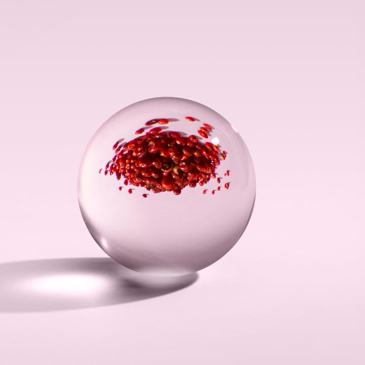 Molton Brown Fiery Pink Pepper Hand Cream 40 ml pleiende håndkrem vist med rosa pepperkorn i en svevende glasskule