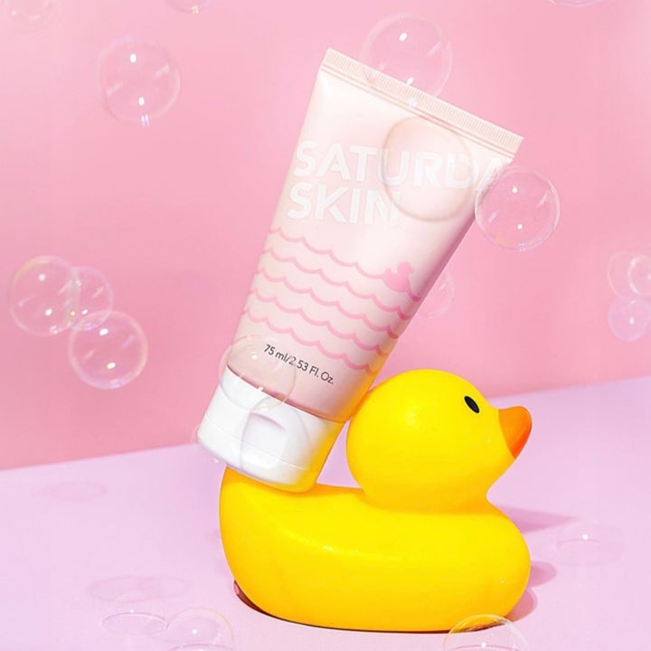 Saturday Skin Rub-a-Dub Refining Peel Gel 75 ml eksfolierende peelinggel balansert på en gul badeand med bobler.