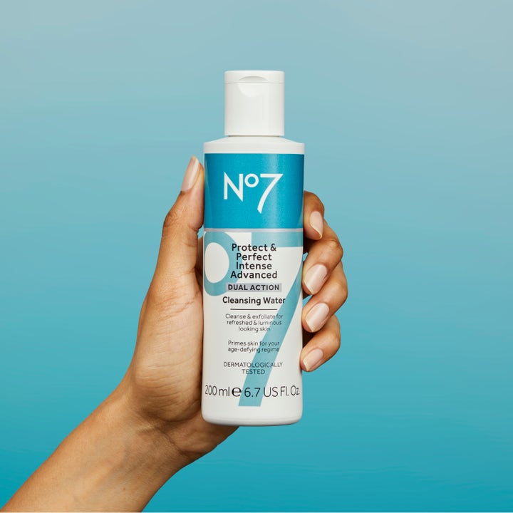 No7 Protect & Perfect Intense Advanced Cleansing Water 200 ml ansiktsrens som gir glød i hvit flaske holdt mot blå bakgrunn
