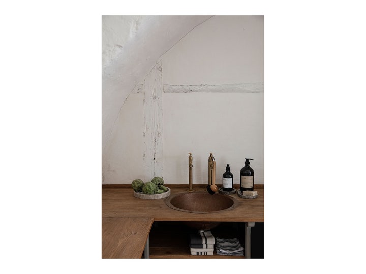 Meraki Blossom Breeze Dish Wash 1000 ml oppvaskmiddel i mørk pumpeflaske på en rustikk trebenk ved en vask.