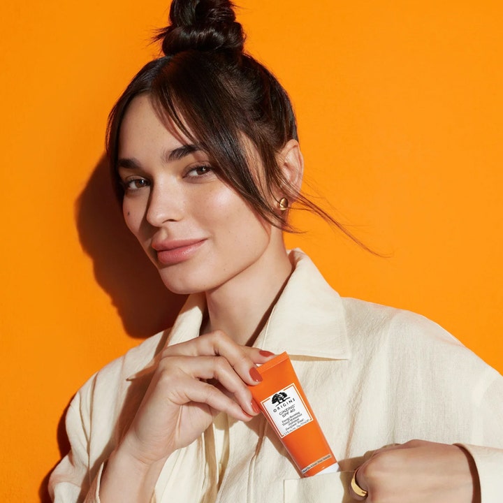 Origins GinZing SPF40 Energy-Boosting Tinted Moisturizer 50 ml energigivende dagkrem i oransje tube holdt av en kvinne