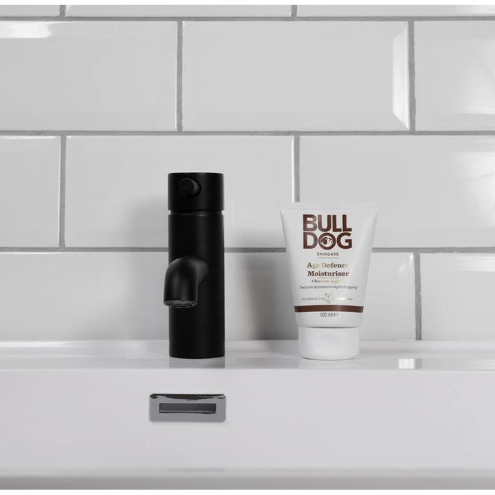 Bulldog Age Defence Moisturiser 100 ml ansiktskrem mot aldringstegn i hvit tube på hvit vask ved siden av sort kran