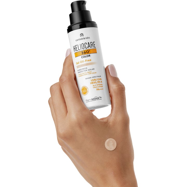 Heliocare Gel Oil-Free SPF 50+ Bronze 50 ml solkrem i hvit pumpeflaske holdt i en hånd med farget tekstur.