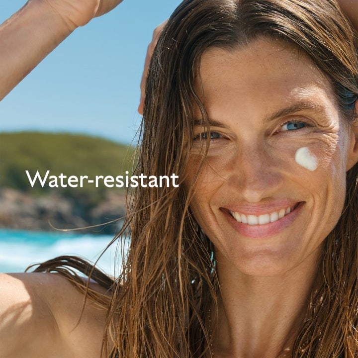 Caudalie Vinosun High Protection Glow Oil 150 ml vannresistent sololje på smilende kvinne med vått hår på stranden