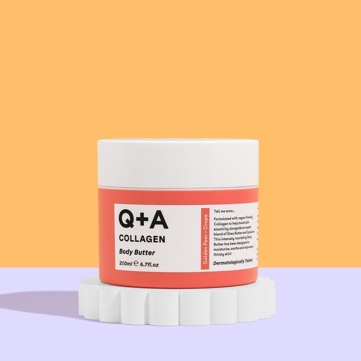 Q+A Collagen Body Butter 200 ml fuktighetsgivende kroppskrem i ferskenfarget krukke med hvitt lokk på en hvit sokkel.