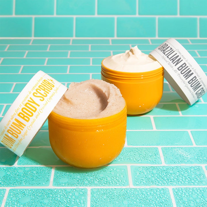 Sol de Janeiro Bum Bum Body Scrub 220 g eksfolierer med sukkerkrystaller i gul krukke ved siden av krem.