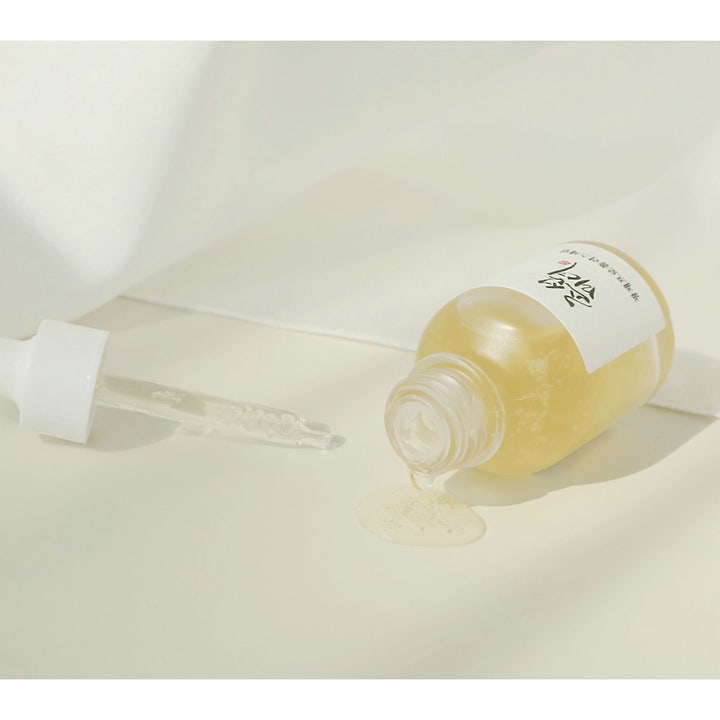 Beauty of Joseon Glow Serum 30ml gir glød med honninglignende gul tekstur som renner ut fra en liggende glassflaske.