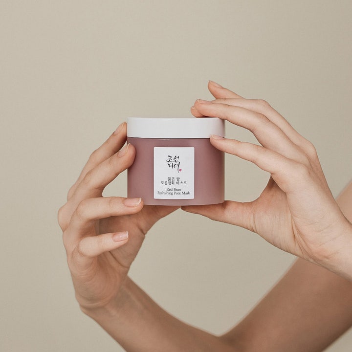 Beauty of Joseon Red Bean Refreshing Pore Mask 140 ml rensende ansiktsmaske i lilla krukke med hvitt lokk holdt av hender