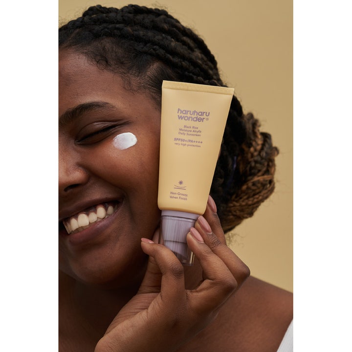 Haruharu wonder Black Rice Sunscreen 50 ml fuktighetsgivende solkrem med SPF50 og fløyelsfinish på en smilende kvinne.