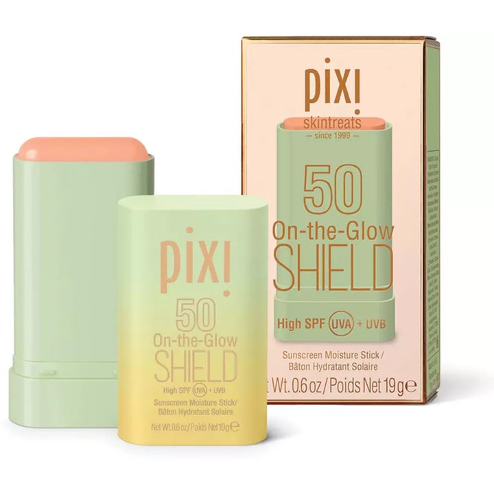 Pixi On-the-Glow Shield 19 g beskyttende solkrem stift SPF 50 i lysegrønn hylse ved siden av den rosa esken.