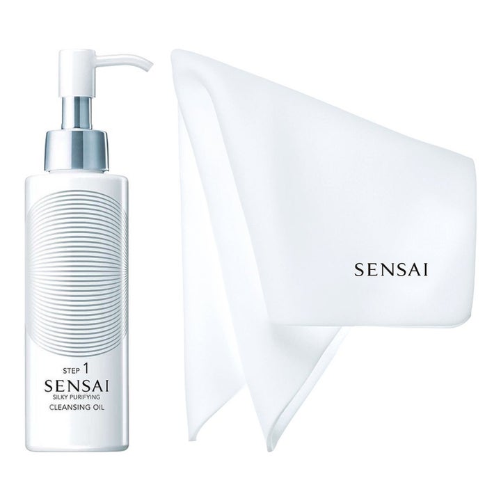 Sensai Silky Purifying Cleansing Oil ansiktsrens i hvit pumpeflaske med sølvdetaljer ved siden av hvit renseklut