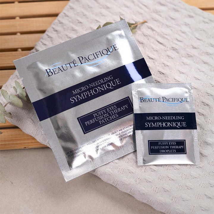 Beauté Pacifique Symphonique Micro Needling Puffy Eyes kit i sølvfargede poser mot poser under øynene på et håndkle