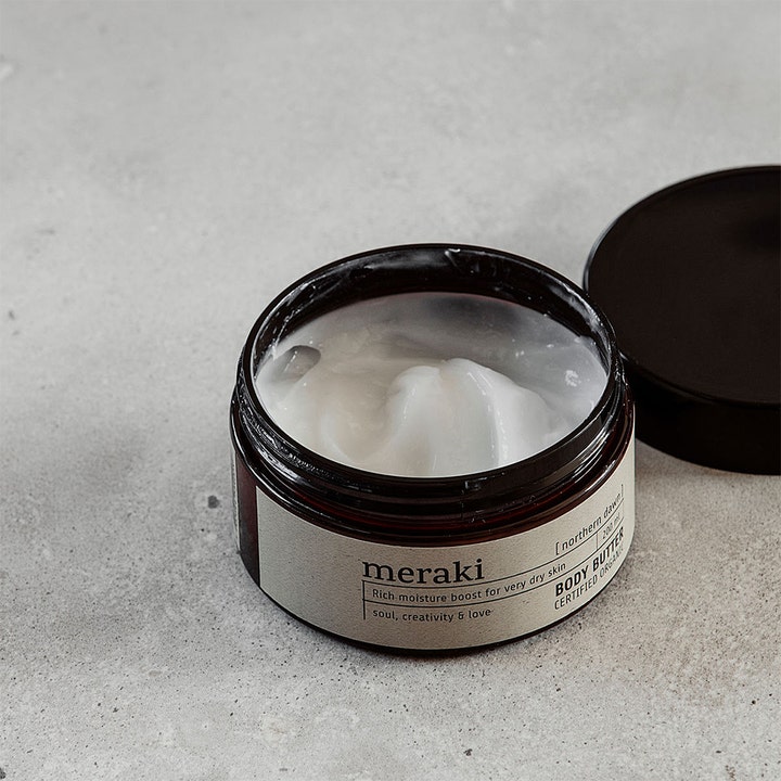Meraki Northern Dawn Body Butter 200 ml gir fukt til tørr hud med en fyldig hvit tekstur i en mørk krukke.