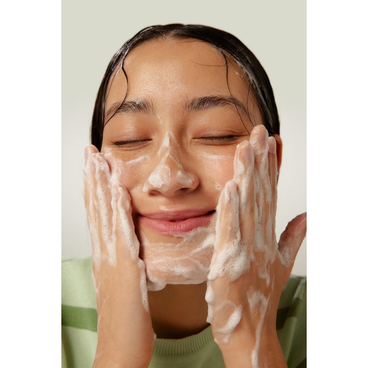 By Wishtrend Green Tea Enzyme Powder Wash 110 g ansiktsrens gir glød idet en kvinne masserer hvitt skum over ansiktet