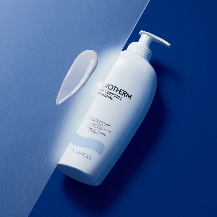 Biotherm Lait Corporel 400 ml fuktighetsgivende bodylotion hvit pumpeflaske med en hvit kremet teksturprøve på blå bakgrunn