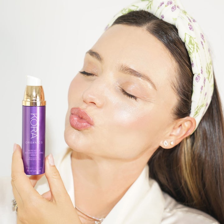 KORA Organics Noni Night AHA Resurfacing Serum 30 ml eksfolierende nattserum i lilla flaske holdt av kvinne