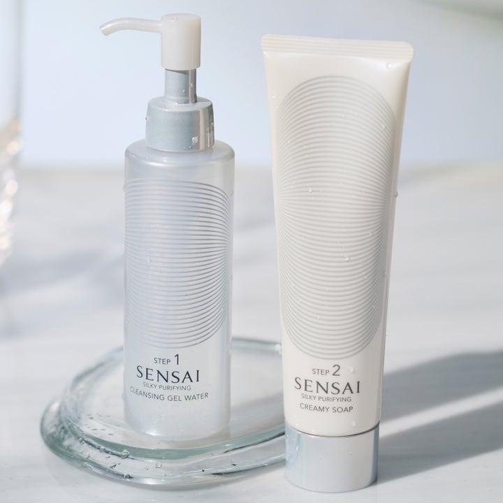 Sensai Silky Purifying Creamy Soap 125 ml ansiktsrens i hvit tube ved siden av rensegel på et glassfat