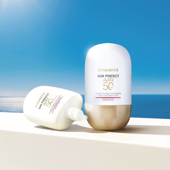 Lancaster Sun Perfect AIR Daily Invisible Fluid 40 ml solkrem ansikt SPF50 i hvite og gullflasker mot havlandskap.