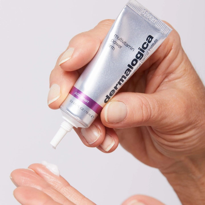 Dermalogica AGE smart Multivitamin Power Firm 15 ml oppstrammende øyekrem i sølvtube med hvit krem på en finger