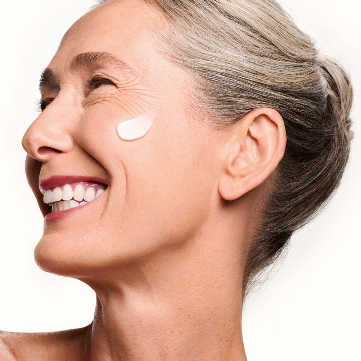 Shiseido Vital Perfection Supreme Cream 50 ml oppstrammende dagkrem på kinnet til en smilende kvinne med grått hår