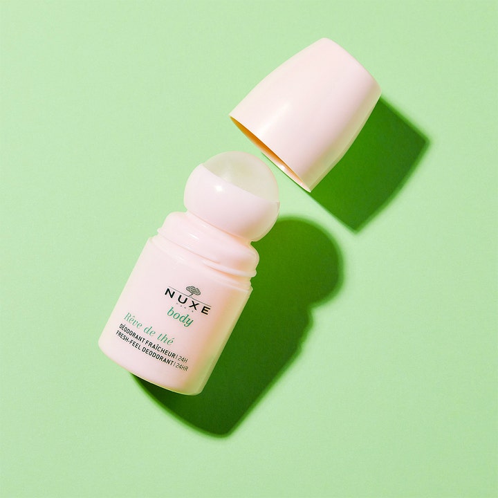 Nuxe Body Reve De Thé Fresh Deodorant 50 ml roll-on i lyserosa forpakning med åpen kork på grønn bakgrunn