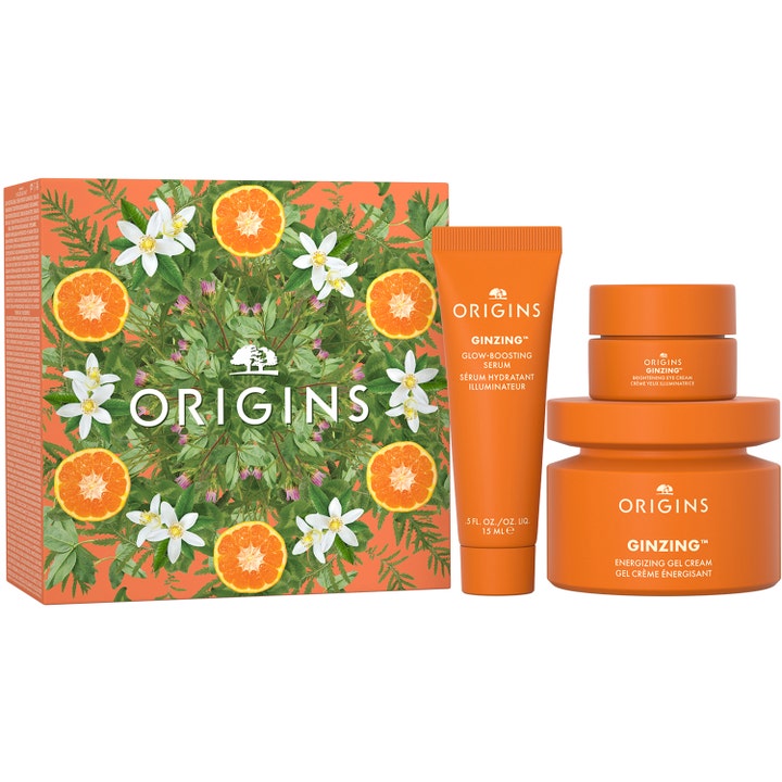 Origins Ginzing Glow-Boosting Essentials hudpleiesett som gir glød med oransje krukker og tube foran en dekorativ eske.