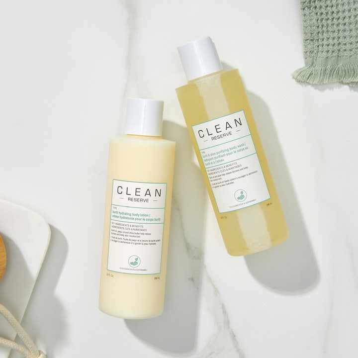 Clean Reserve Buriti & Aloe Shower Gel 296 ml og body lotion på hvit marmorflate ved en vaskeklut