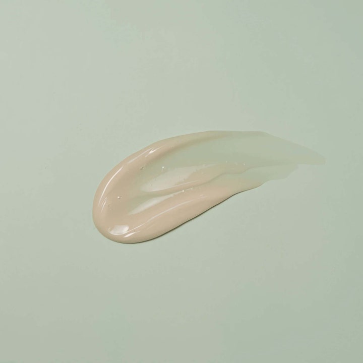 Round Lab Mugwort Calming Cream 80 ml beroligende ansiktskrem med en smidig beige gel-tekstur på grønn bakgrunn
