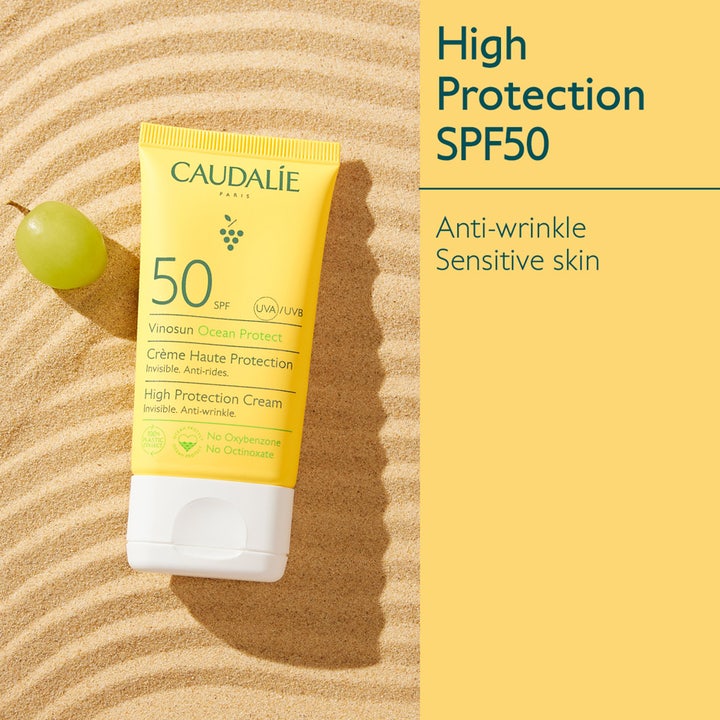 Caudalie Vinosun Protect Cream SPF50+ 50 ml anti-rynke solkrem i gul tube plassert på sand ved siden av en grønn drue.