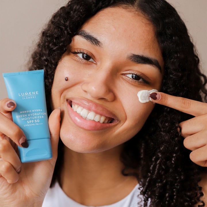 Lumene Nordic Hydra Fresh Hydration Moisturizer SPF50 50 ml solbeskyttelse kvinne som påfører krem fra lyseblå tube